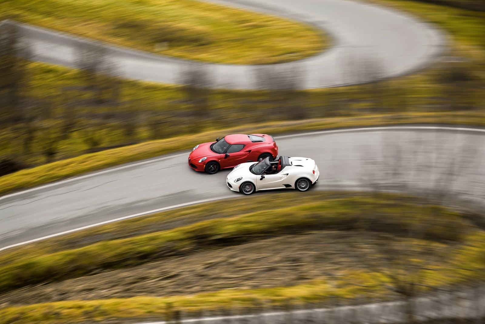 Dos Alfa Romeo 4C compitiendo en una carretera de montaña serpenteante.