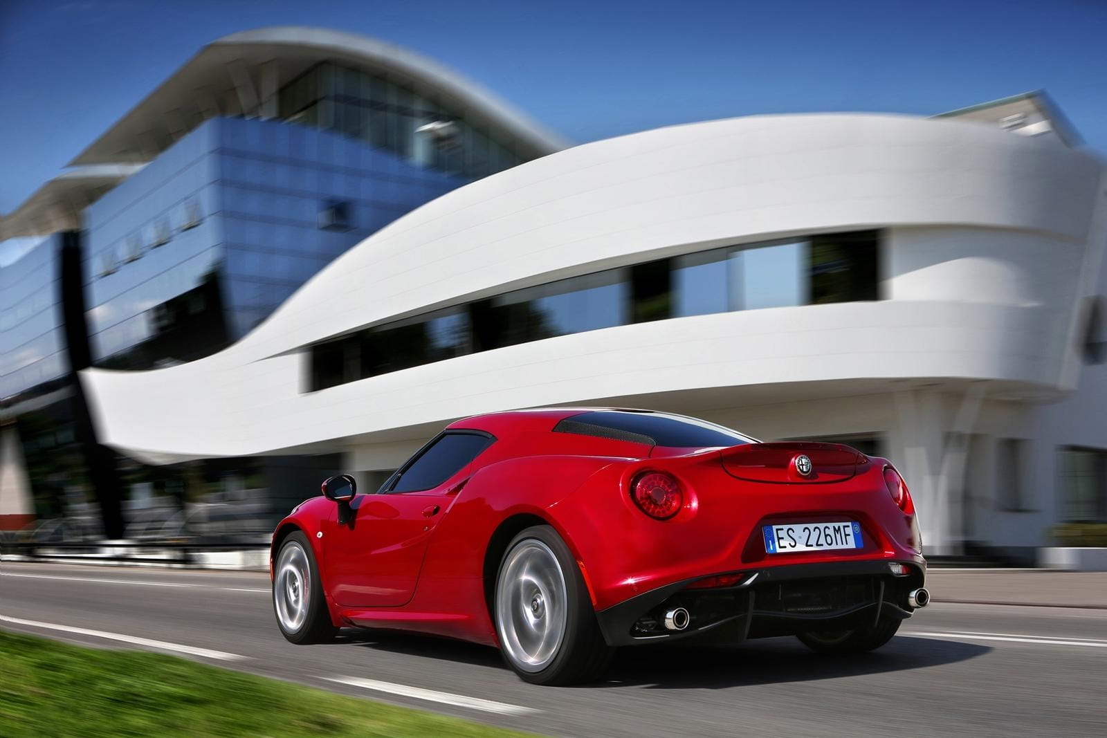 Vista lateral trasera del Alfa Romeo 4C en un entorno urbano moderno.