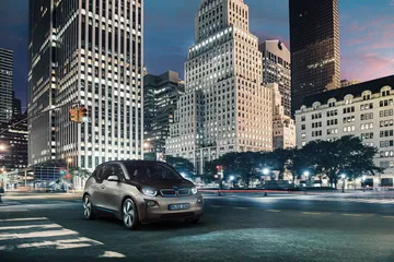 Imagen del BMW i3 circulando por la ciudad de noche iluminada.