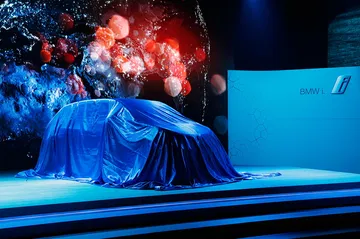 BMW i3 a punto de ser desvelado, cubierto con una lona azul que genera expectativa.