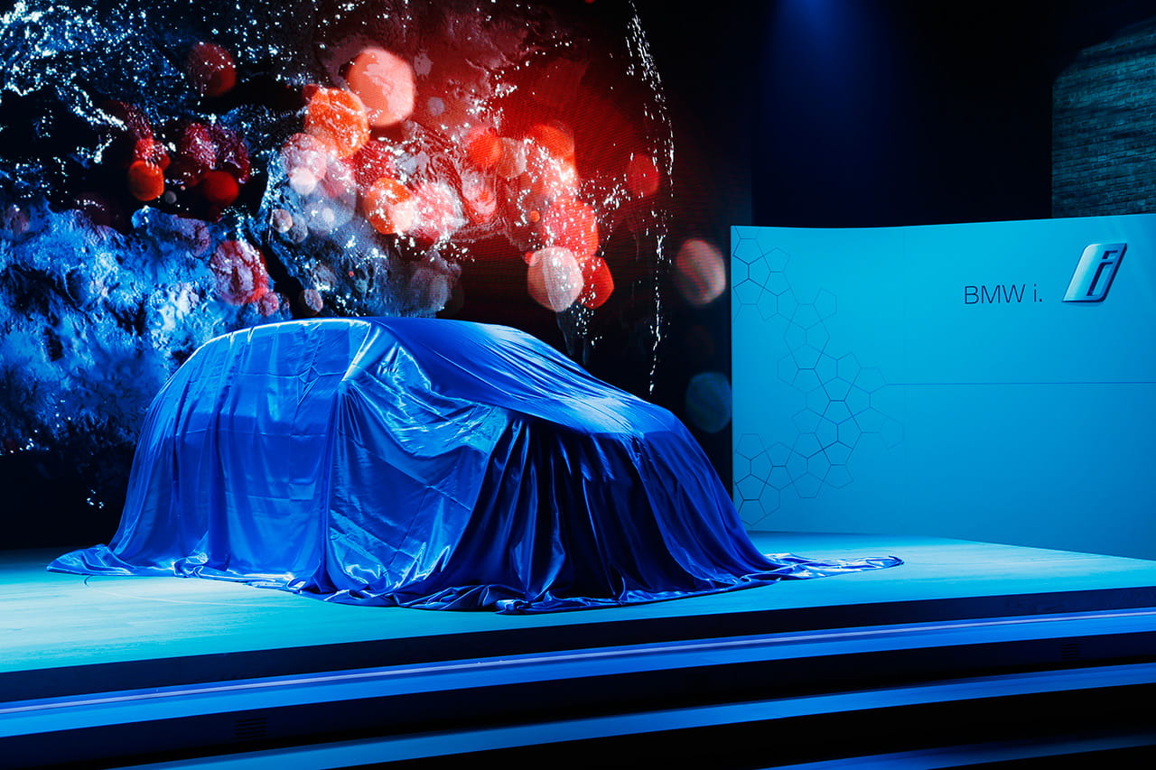 BMW i3 a punto de ser desvelado, cubierto con una lona azul que genera expectativa.