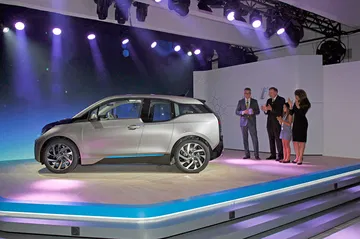BMW i3 en presentación oficial, vista lateral con público y presentadores.