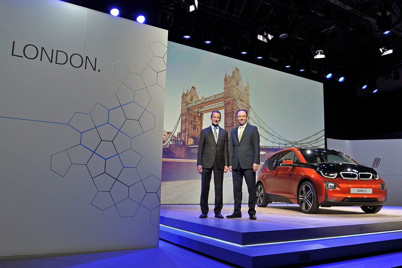 BMW i3 en presentación oficial con dos personas al lado, destacando su diseño lateral.