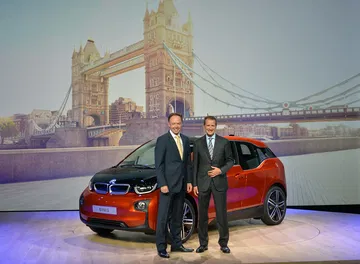 Vista lateral del BMW i3 en su presentación mundial, con dos personas al lado.