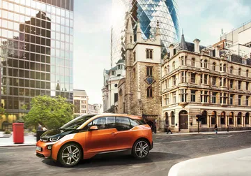 Vista lateral del BMW i3 en un escenario urbano, resaltando su diseño compacto y moderno.