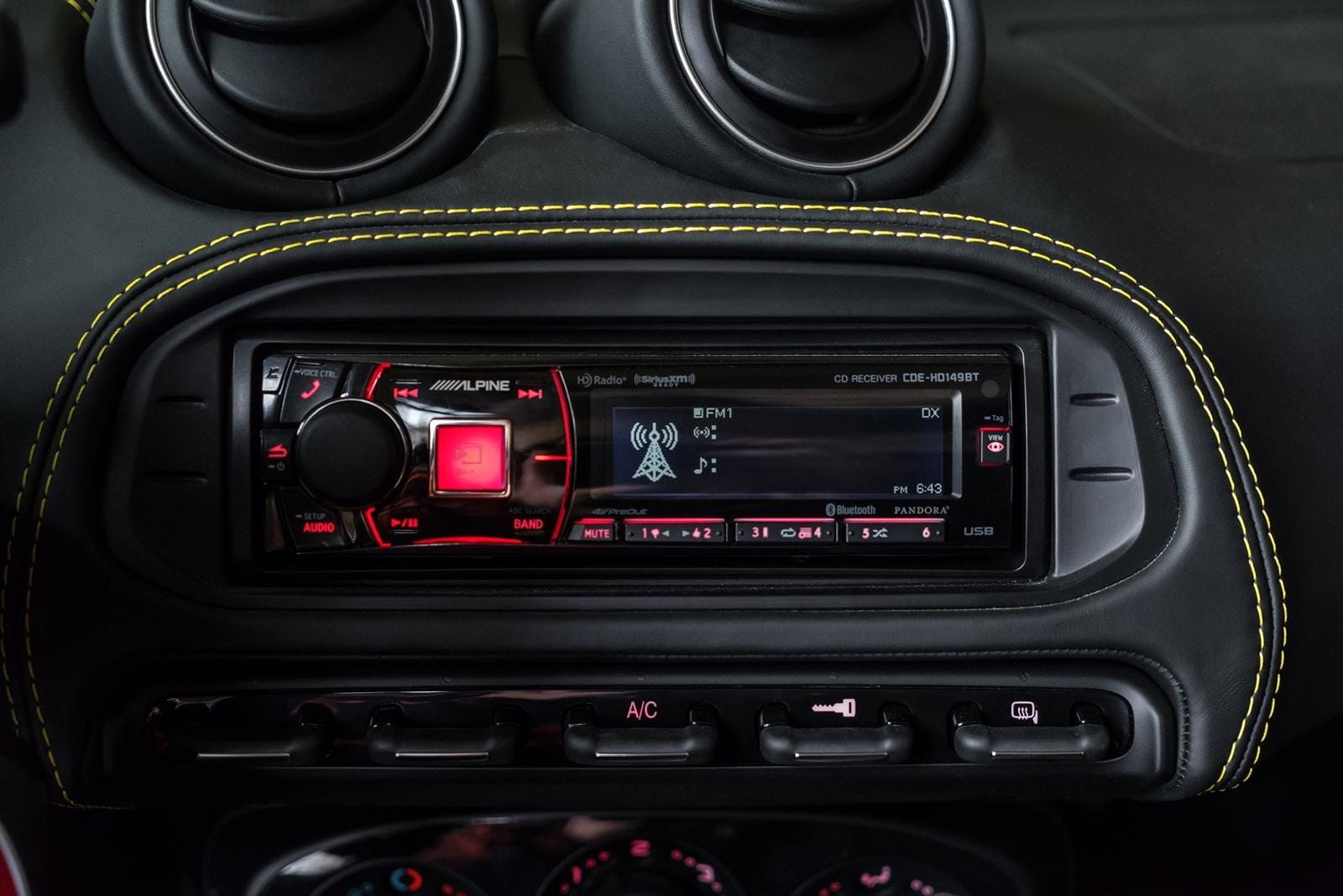 Consola central con pantalla y controles del Alfa Romeo 4C, acabado en fibra de carbono.