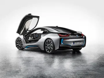 Vista trasera y lateral de un BMW i8 con las puertas en ala de gaviota abiertas.