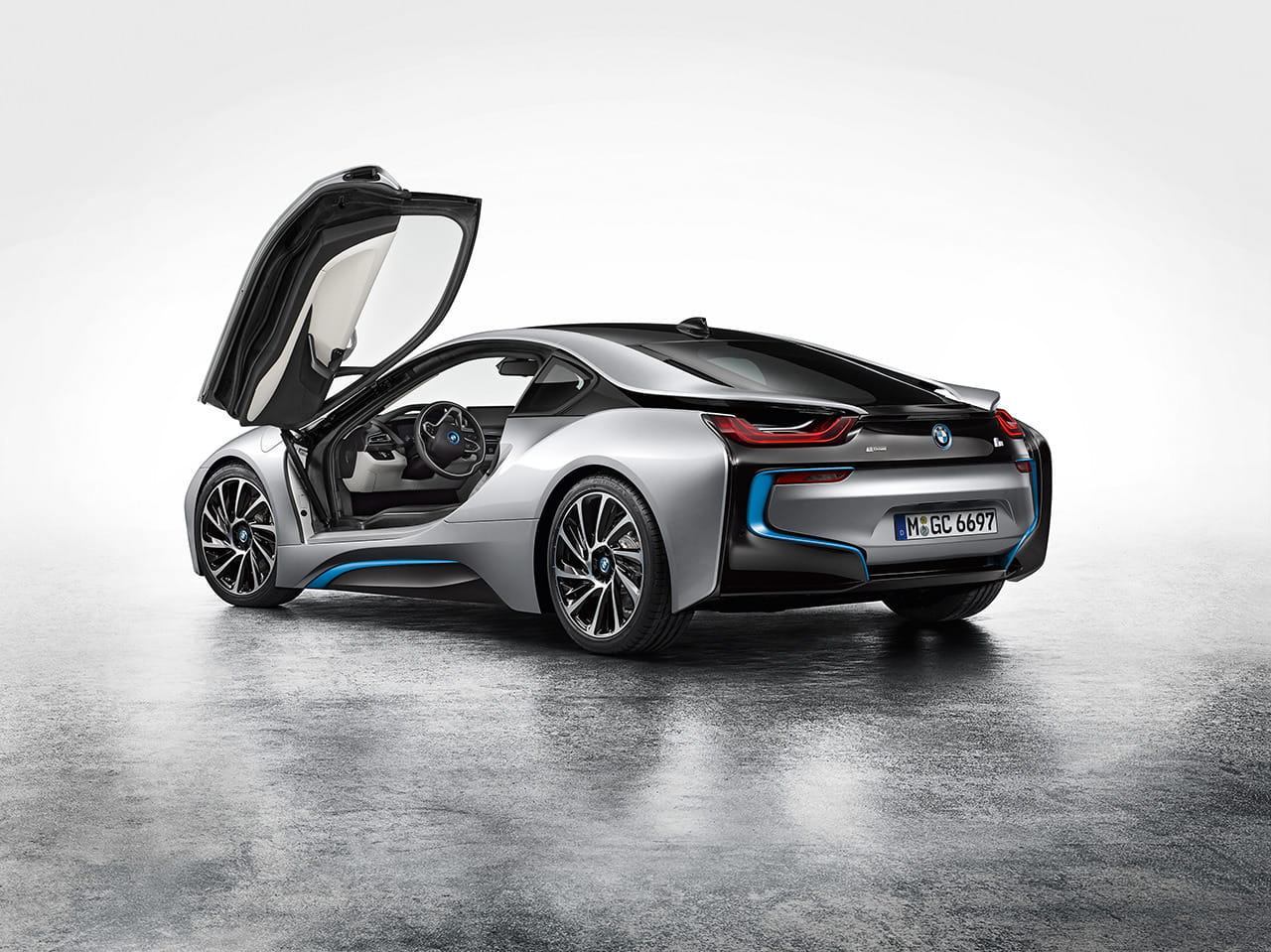 Vista trasera y lateral de un BMW i8 con las puertas en ala de gaviota abiertas.
