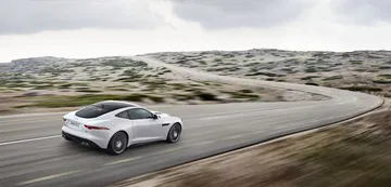 Vista dinámica lateral del Jaguar F-Type Coupé en carretera.