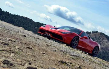 Vista lateral del Ferrari 458 Italia en un entorno montañoso.