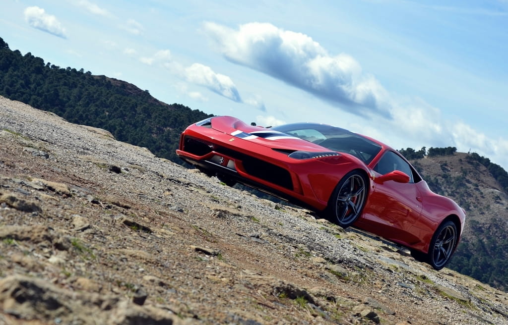 Vista lateral del Ferrari 458 Italia en un entorno montañoso.