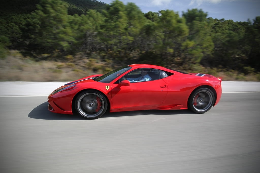 Ferrari 458 Italia en movimiento, captura lateral que muestra su diseño aerodinámico.