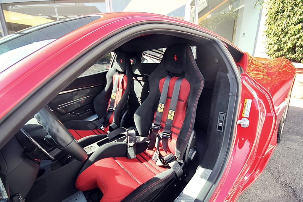 Vista lateral del habitáculo del Ferrari 458 Italia con asientos de cuero rojo.