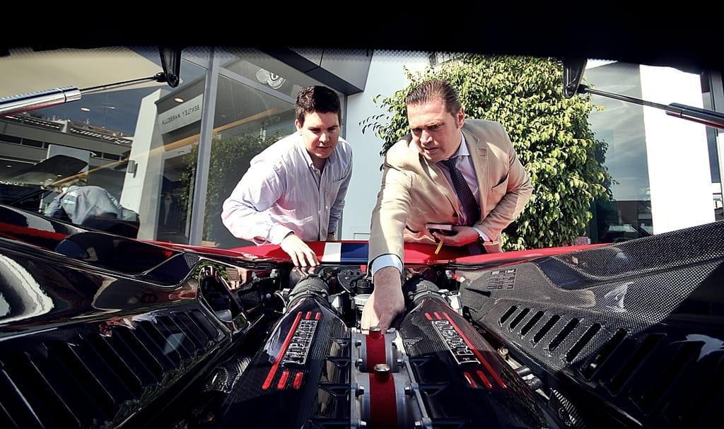 Dos personas observando atentamente el motor del Ferrari 458 Italia.