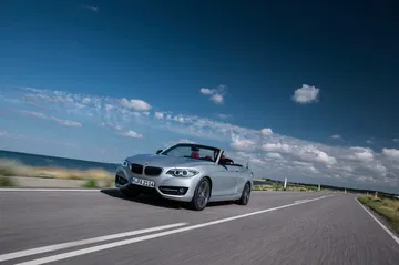 Vista dinámica del BMW Serie 2 Cabrio, enfatizando su diseño frontal y lateral.
