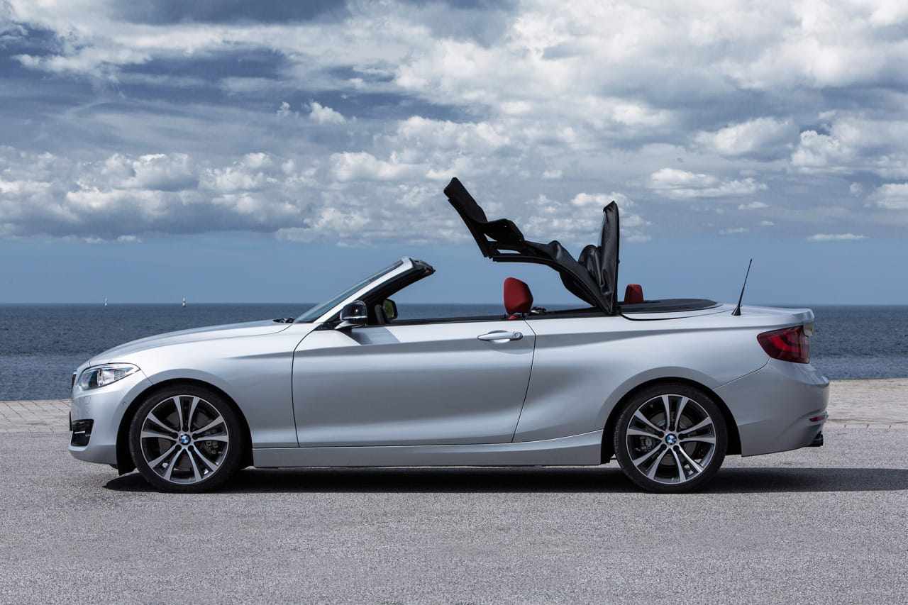 Vista lateral del BMW Serie 2 Cabrio con capota bajada, destacando su diseño dinámico.