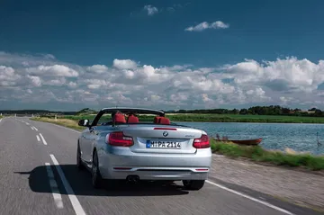 Vista trasera y lateral del BMW Serie 2 Cabrio en carretera