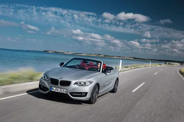 BMW Serie 2 Cabrio en movimiento con el techo bajado y vista lateral delantera.