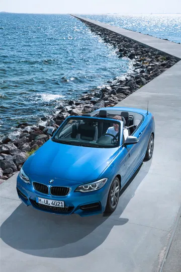 Vista lateral del BMW Serie 2 Cabrio con capota abierta junto al mar.