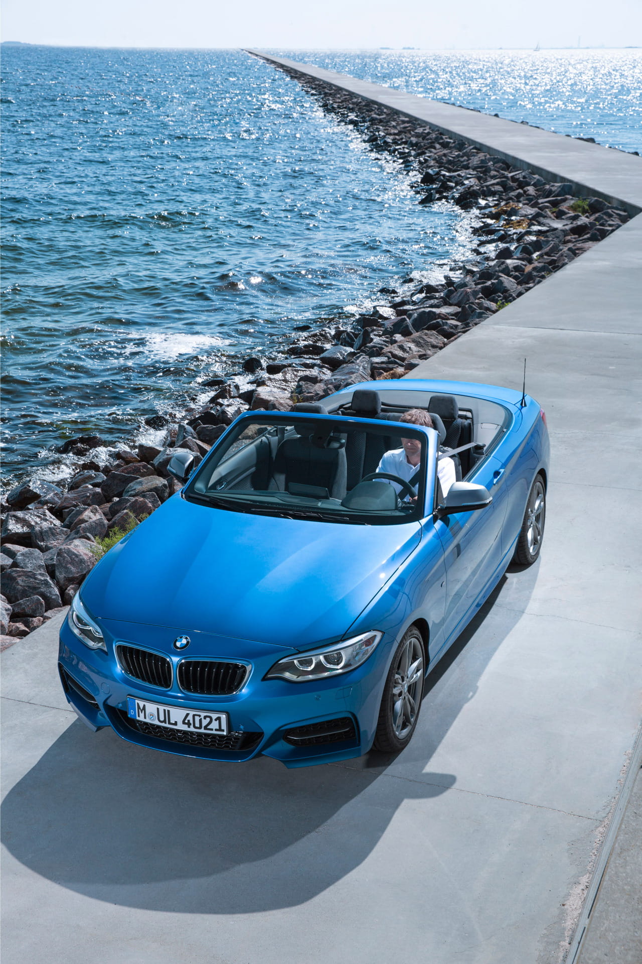 Vista lateral del BMW Serie 2 Cabrio con capota abierta junto al mar.