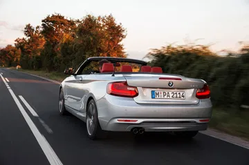Vista dinámica del BMW Serie 2 Cabrio, destacando su diseño trasero y lateral.