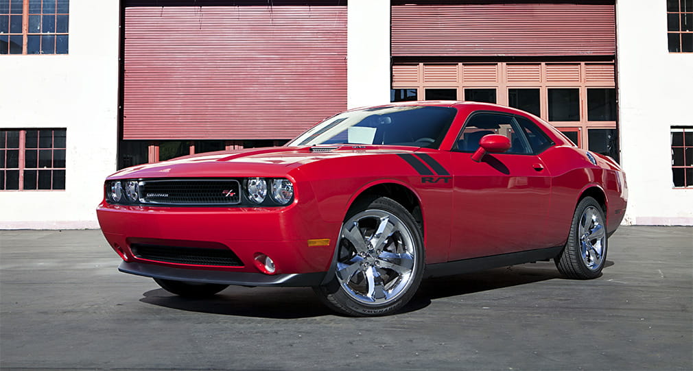 Vista lateral de Dodge Challenger en rojo, mostrando su perfil musculoso y deportivo. Vista lateral de Dodge Challenger en rojo, mostrando su perfil musculoso y deportivo.