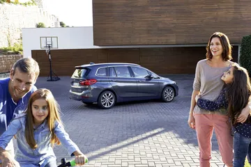 Vista lateral de un BMW Serie 2 Gran Tourer con una familia disfrutando al aire libre