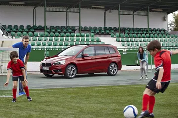 Vista lateral del BMW Serie 2 Gran Tourer en un campo de fútbol