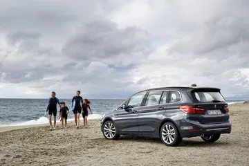 Vista lateral del BMW Serie 2 Gran Tourer frente a la playa, resaltando su diseño familiar.