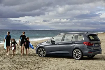 Vista lateral del BMW Serie 2 Gran Tourer en un entorno playero, destacando su línea y diseño.