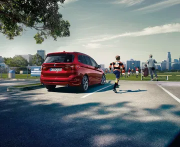 Vista trasera lateral del BMW Serie 2 Gran Tourer en color rojo, estacionado al aire libre.