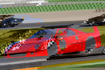 Vista lateral del Ferrari F40 en movimiento en un circuito, destacando su perfil aerodinámico.