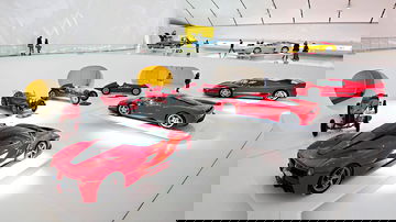 Vista lateral de un Ferrari F40 en una sala de exhibición junto a otros modelos de la marca.