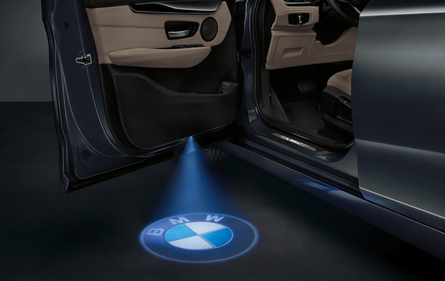 Proyección del emblema BMW al abrir la puerta, un detalle de cortesía elegante.