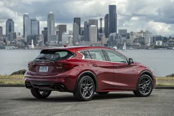 Perfil del Infiniti QX30 con la ciudad de fondo, realzando su diseño urbano.