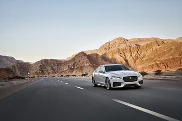 Vista dinámica del Jaguar XF con imponente paisaje montañoso de fondo