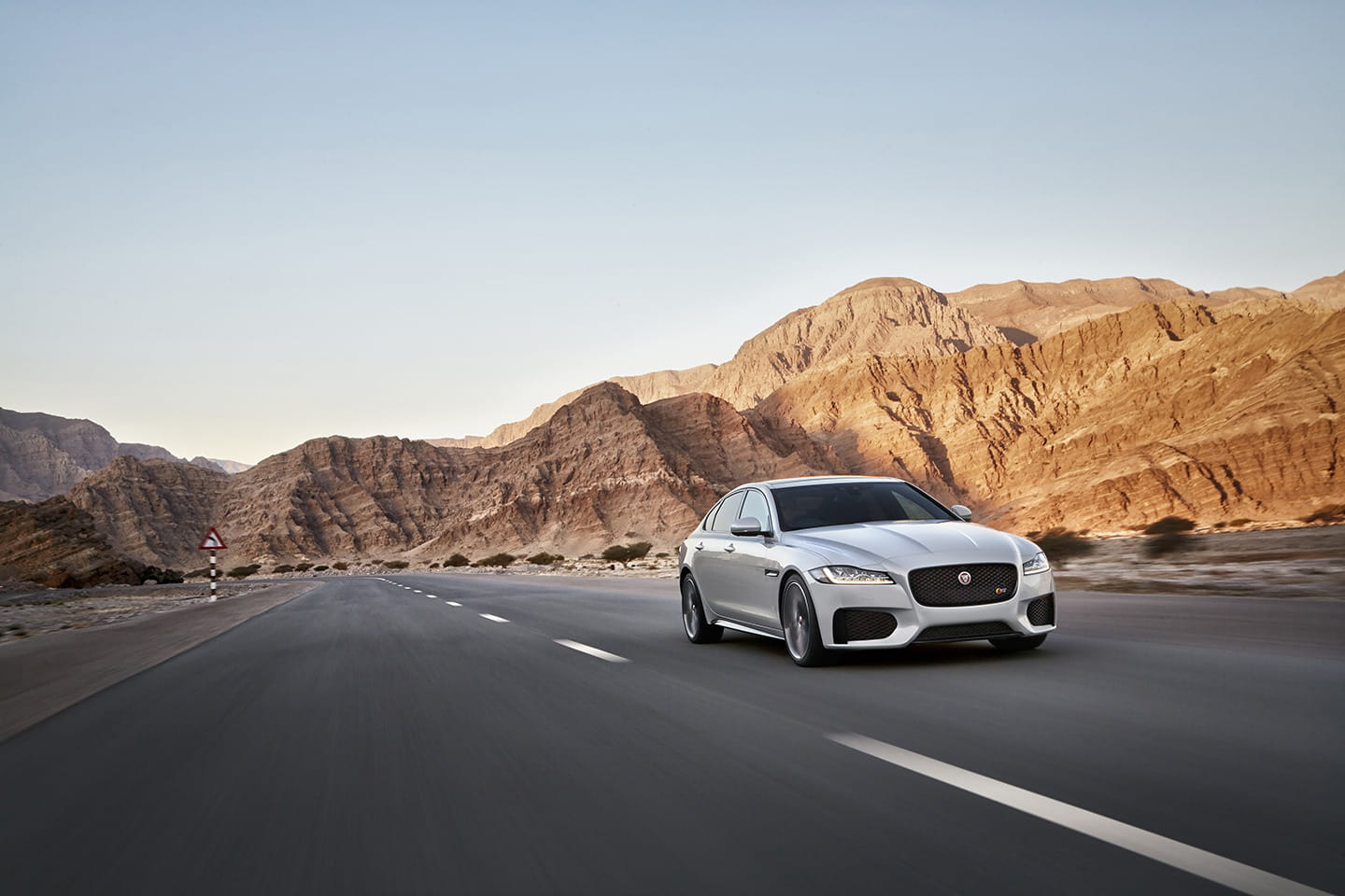 Vista dinámica del Jaguar XF con imponente paisaje montañoso de fondo