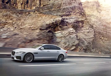 Vista dinámica lateral del Jaguar XF en carretera, enfatizando su diseño aerodinámico.