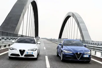 Dos Alfa Romeo Giulia avanzan en paralelo sobre un moderno puente.