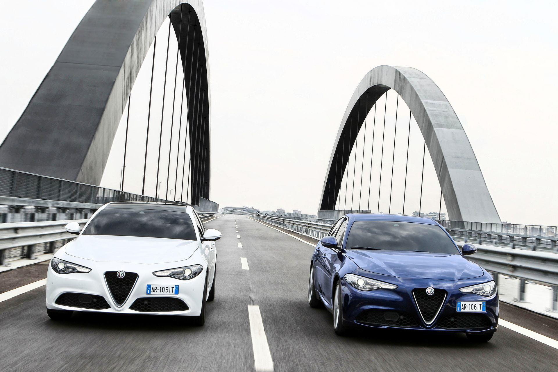 Dos Alfa Romeo Giulia avanzan en paralelo sobre un moderno puente.