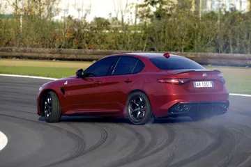 Vista dinámica de un Alfa Romeo Giulia en circuito, destacando su línea deportiva.
