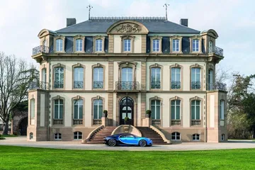 Vista lateral del Bugatti Chiron frente a una imponente mansión.
