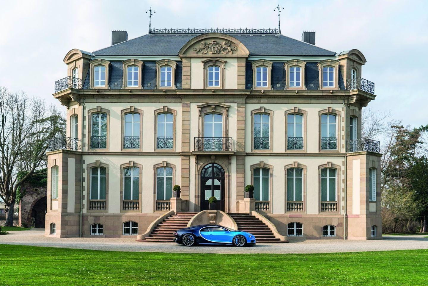 Vista lateral del Bugatti Chiron frente a una imponente mansión.