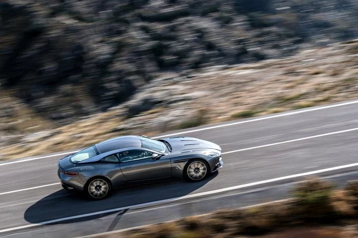 Aston Martin DB11 en movimiento mostrando su estilizada línea lateral.