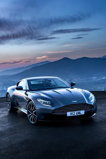 Vista lateral y delantera del Aston Martin DB11 al atardecer, resaltando su silueta aerodinámica.