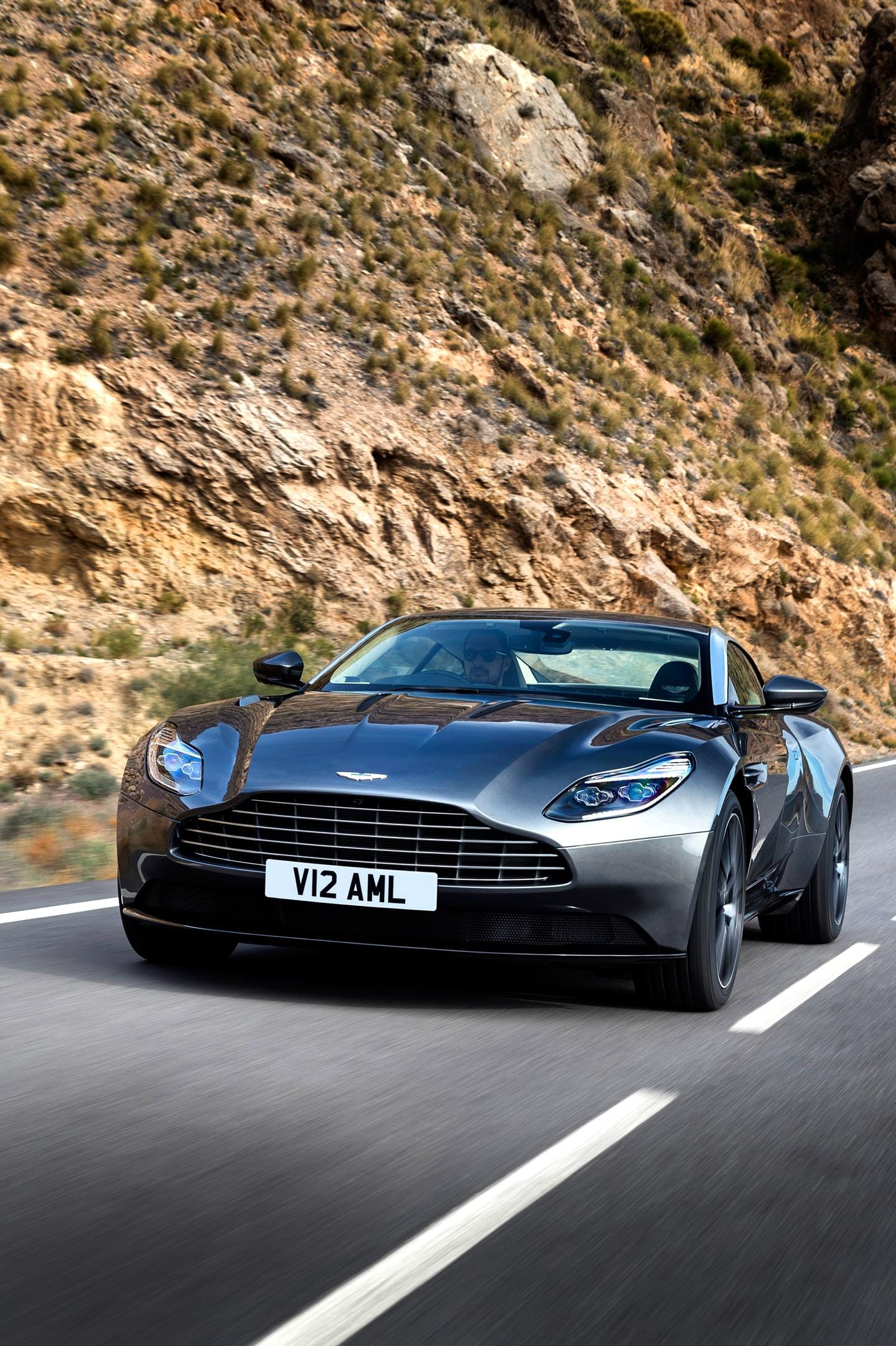 Vista dinámica del Aston Martin DB11 en carretera, enfocando frontal y lateral.