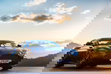 Vista dinámica del Aston Martin DB11 al atardecer, destacando su elegante diseño.