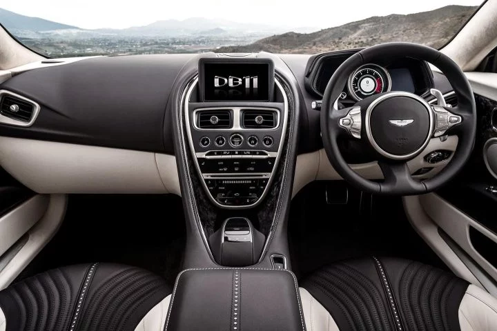 Vista impecable de los asientos deportivos bicolor y consola central del Aston Martin DB11.
