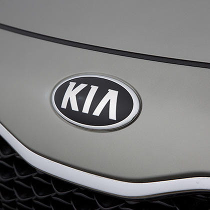 Vista cercana del icónico logo de Kia en el Carens.