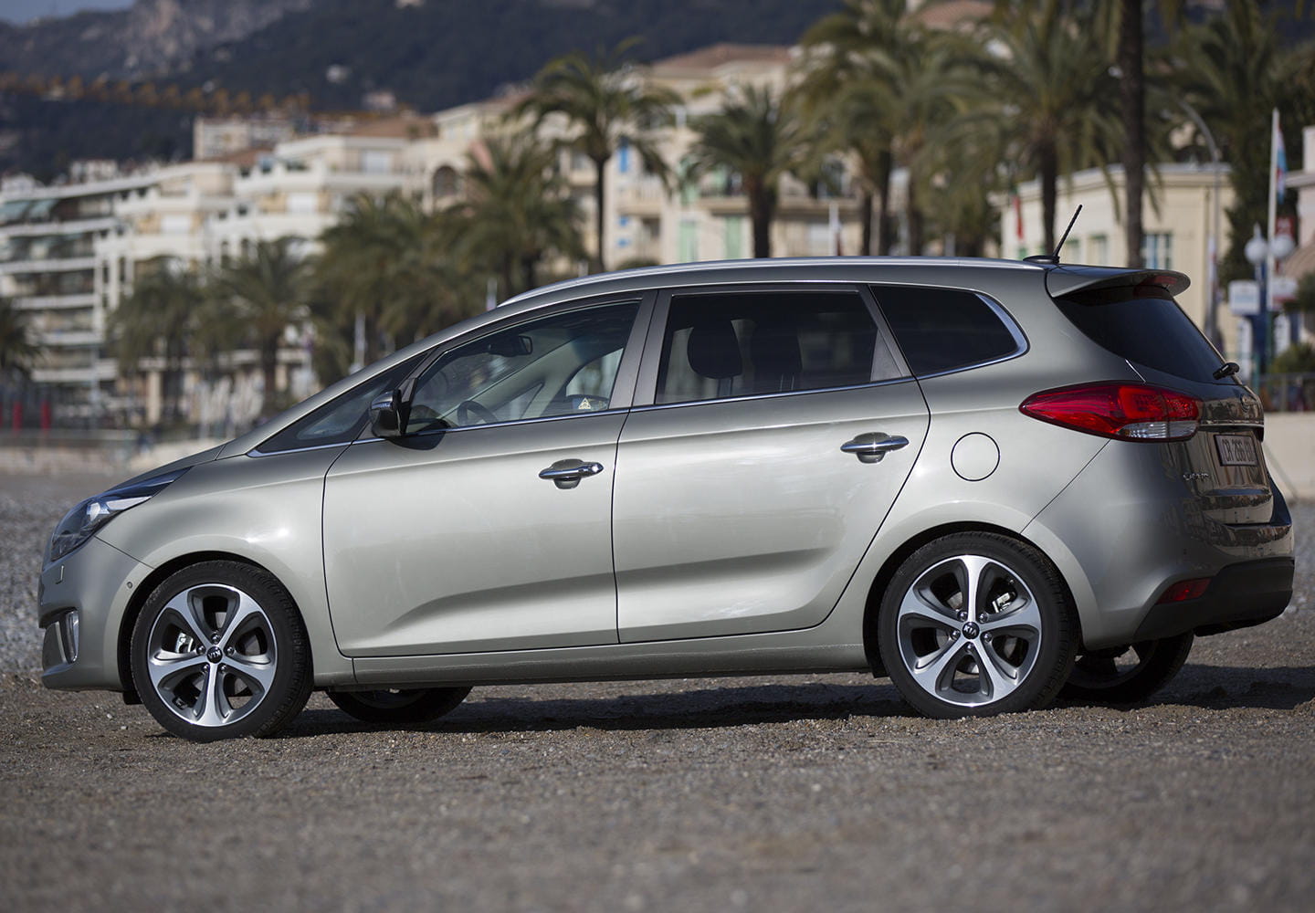 La imagen muestra la perspectiva lateral y trasera del Kia Carens destacando su diseño dinámico.